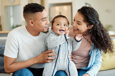 papá y mamá sosteniendo su bebé en el medio de los dos